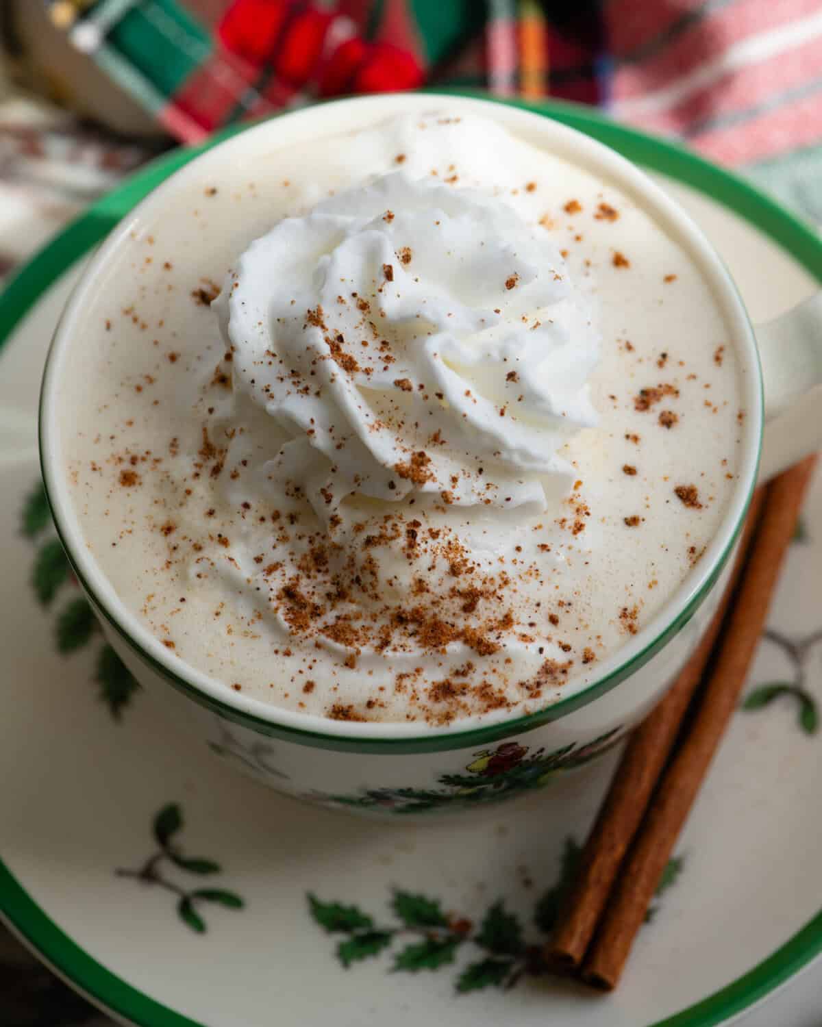 Eggnog in a shallow mug with whipped cream and cinnamon sprinkled on top.