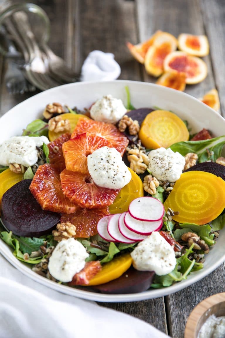 Colorful beet salad with oranges and ricotta in a large white serving bowl.