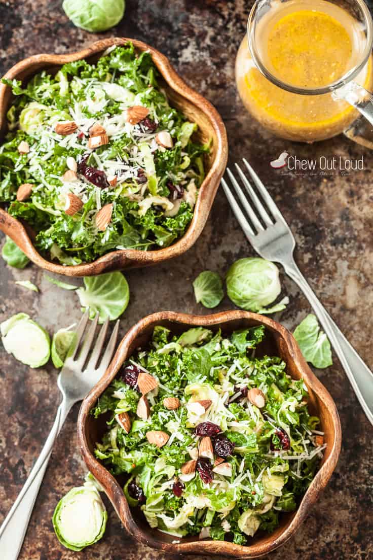 Shaved brussels sprouts salad with parmesan cheese in two daisy-shaped wooden bowls.