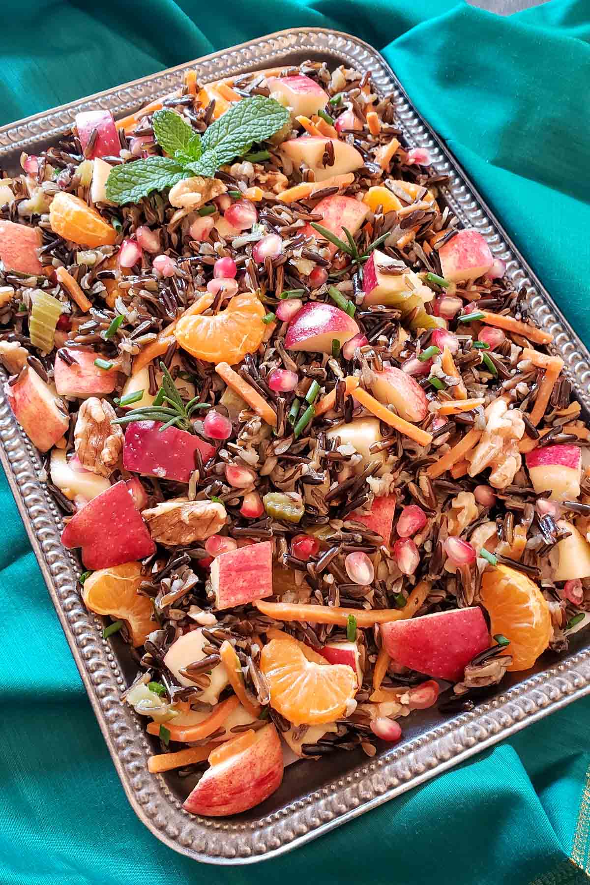 Wild rice salad with apples and mandarin oranges on a large silver tray.