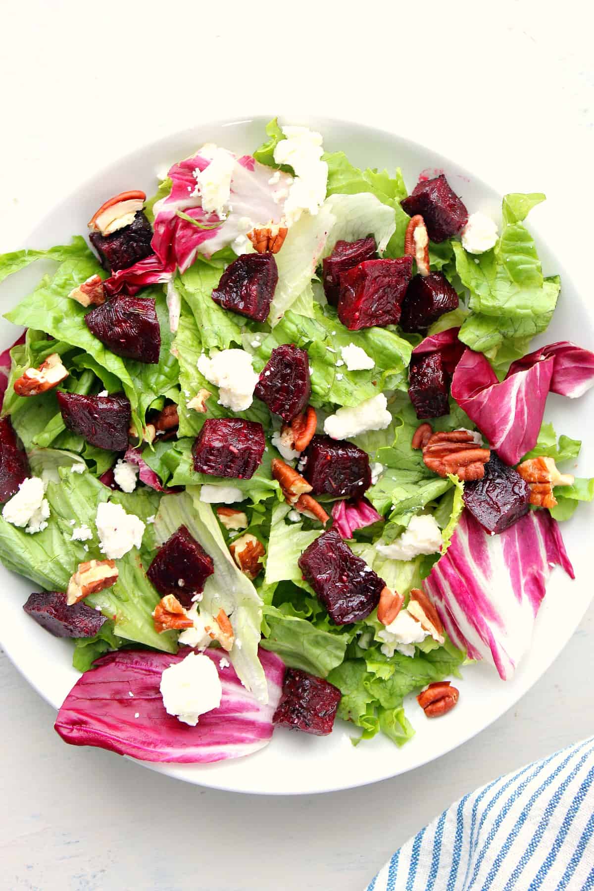 Green beet salad with goat cheese in a white serving dish.