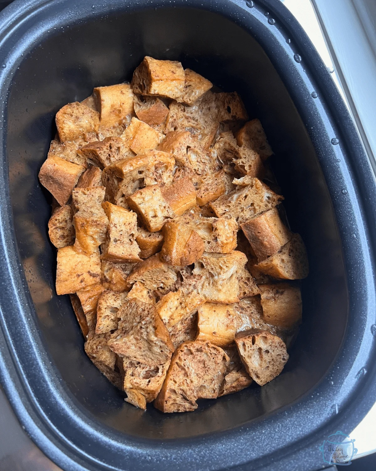 Cubed gingerbread French toast casserole in a black slow cooker.