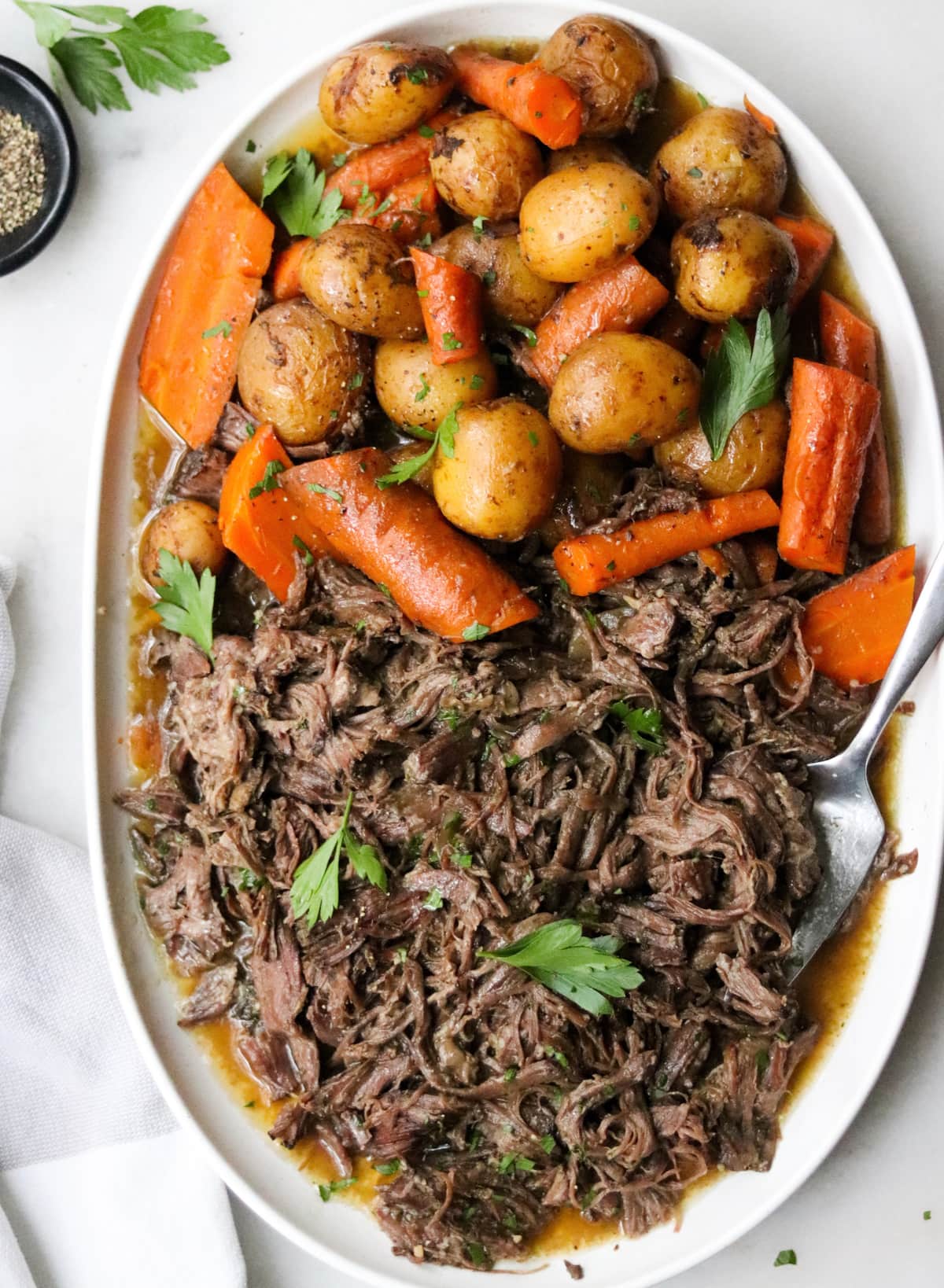 Ranch roasted with potatoes and carrots on a large white oval serving dish.
