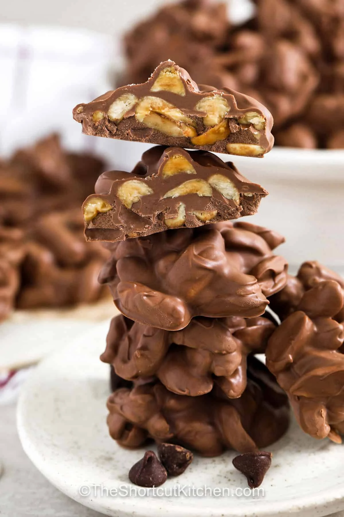 Peanut cluster candies stacked on a white plate.
