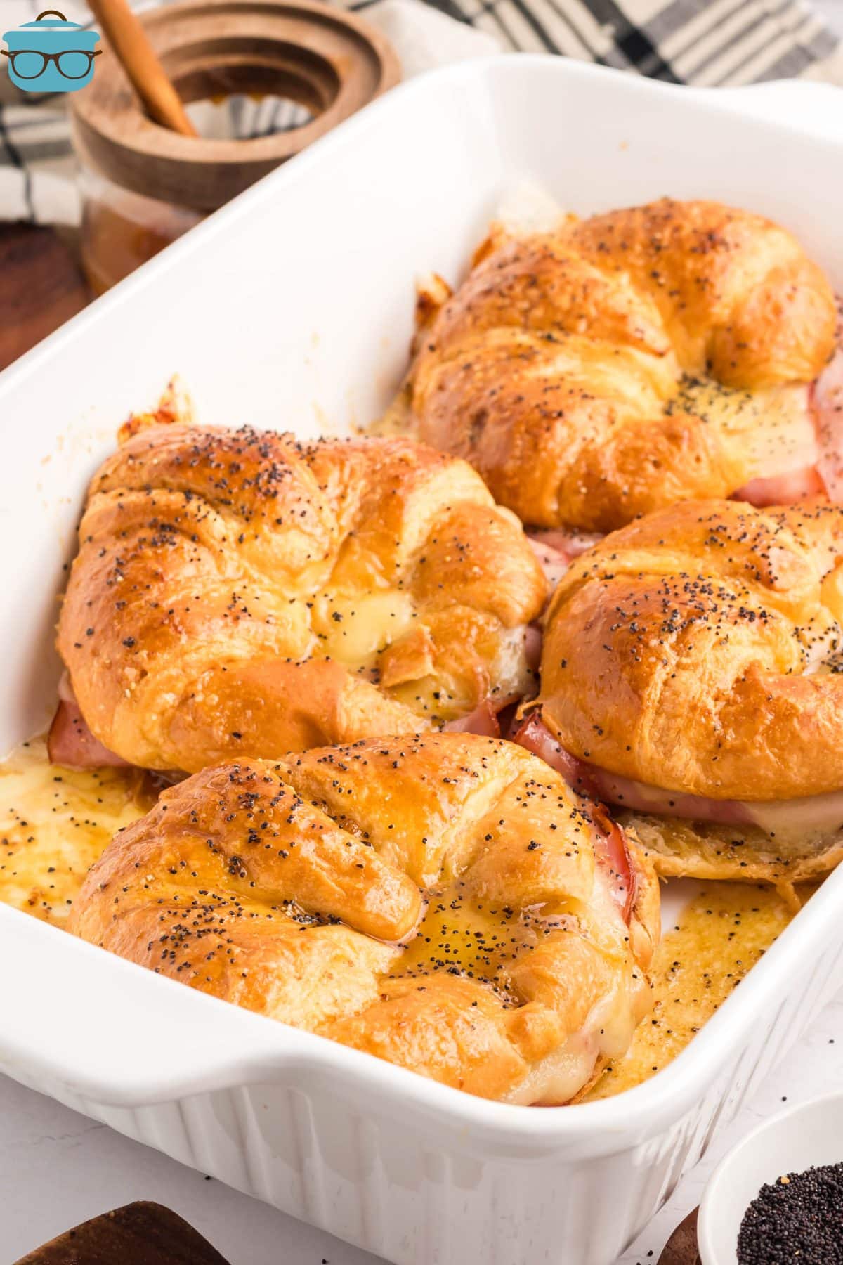 Cheese and ham croissants in a white casserole baking dish.