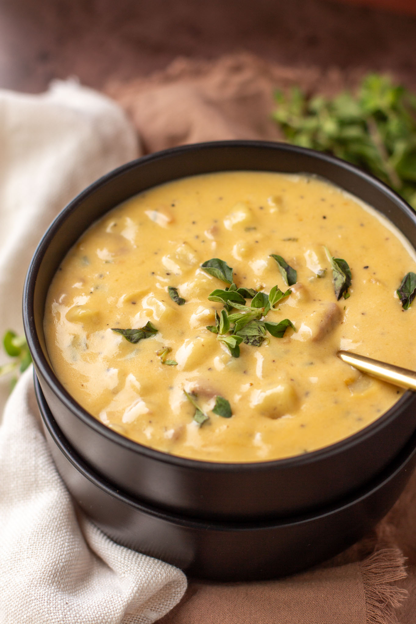 Smoky cheddar and ham soup in a black bowl with green garnish.