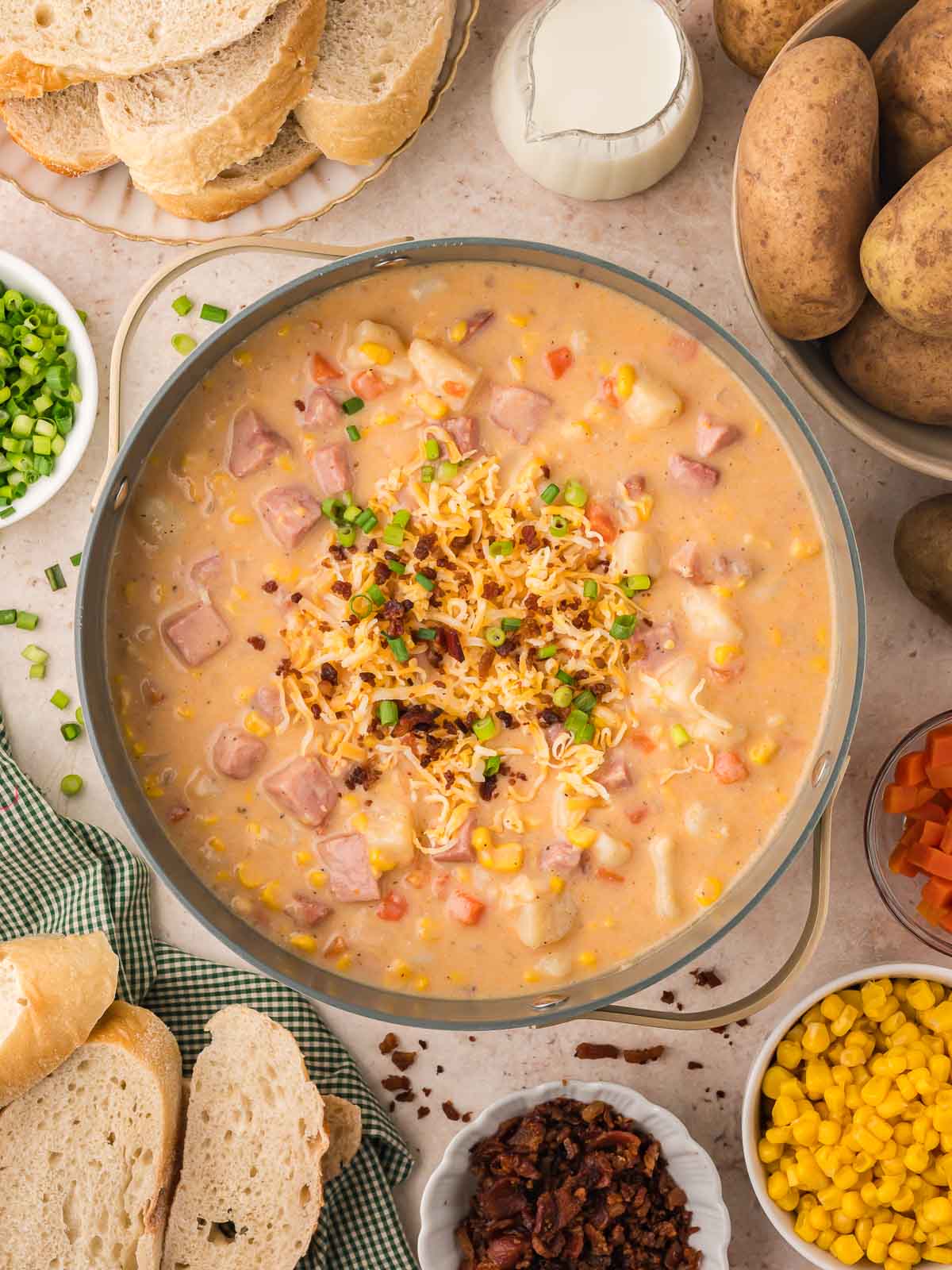 Ham and potato soup in a gray bowl with green garnish and cheese on top.