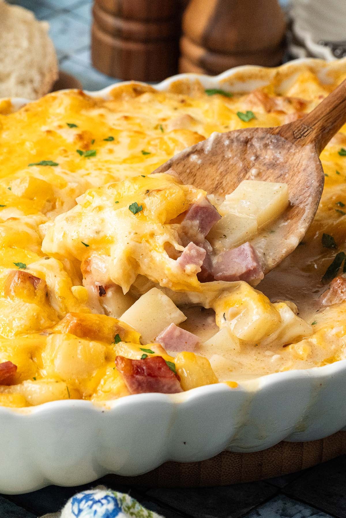 Ham and potato casserole in a baking dish with a wooden spoon.