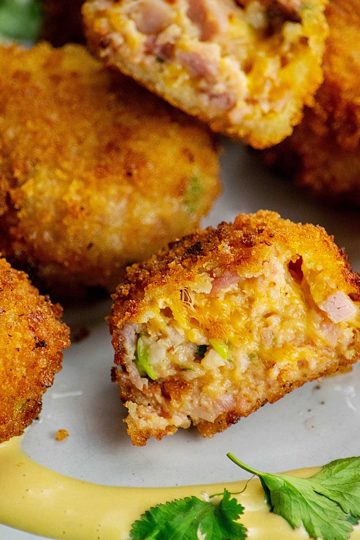 A pile of ham and cheese croquettes on a white platter.