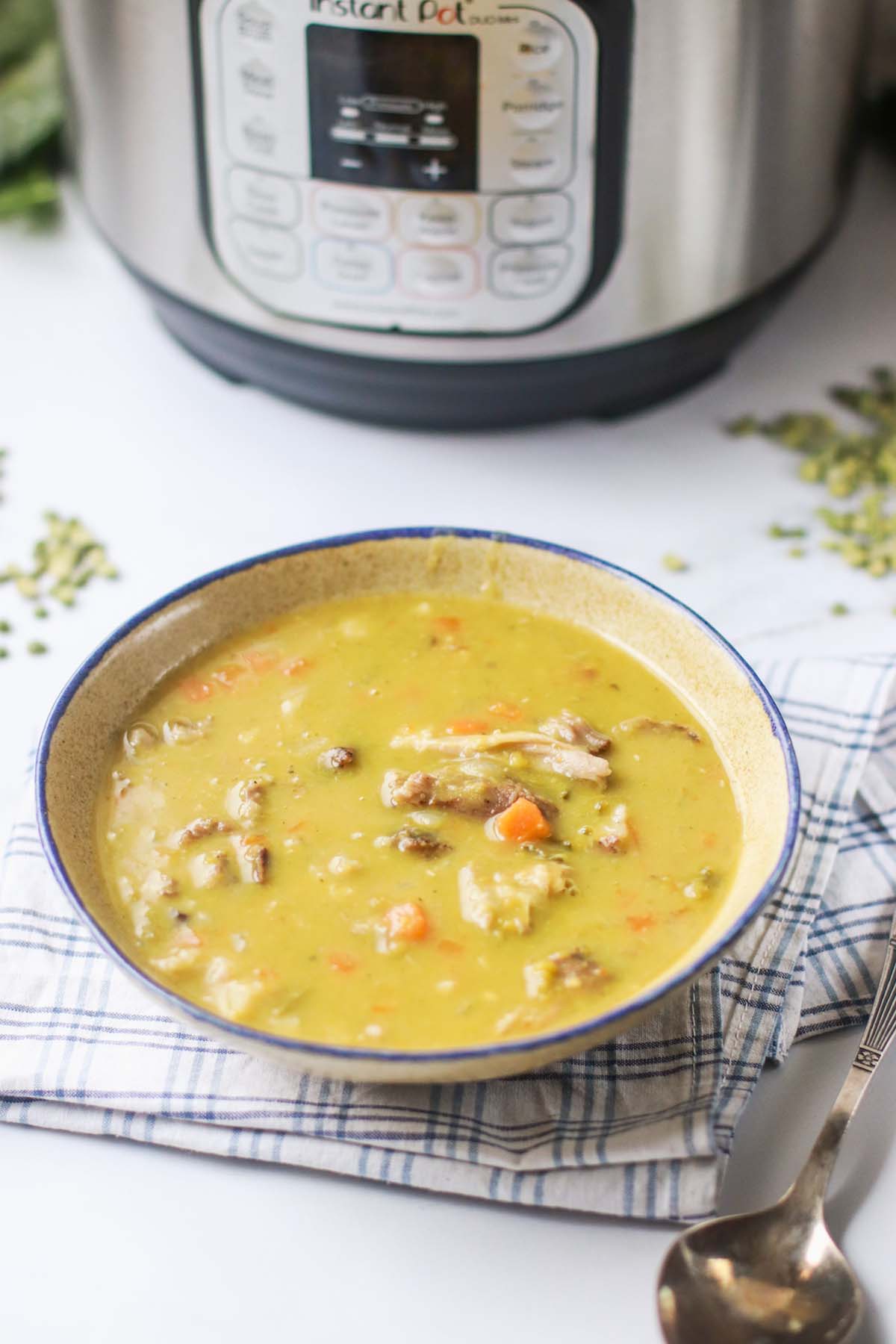 Instant pot ham and green split pea soup in a bowl in front of an Instant Pot.