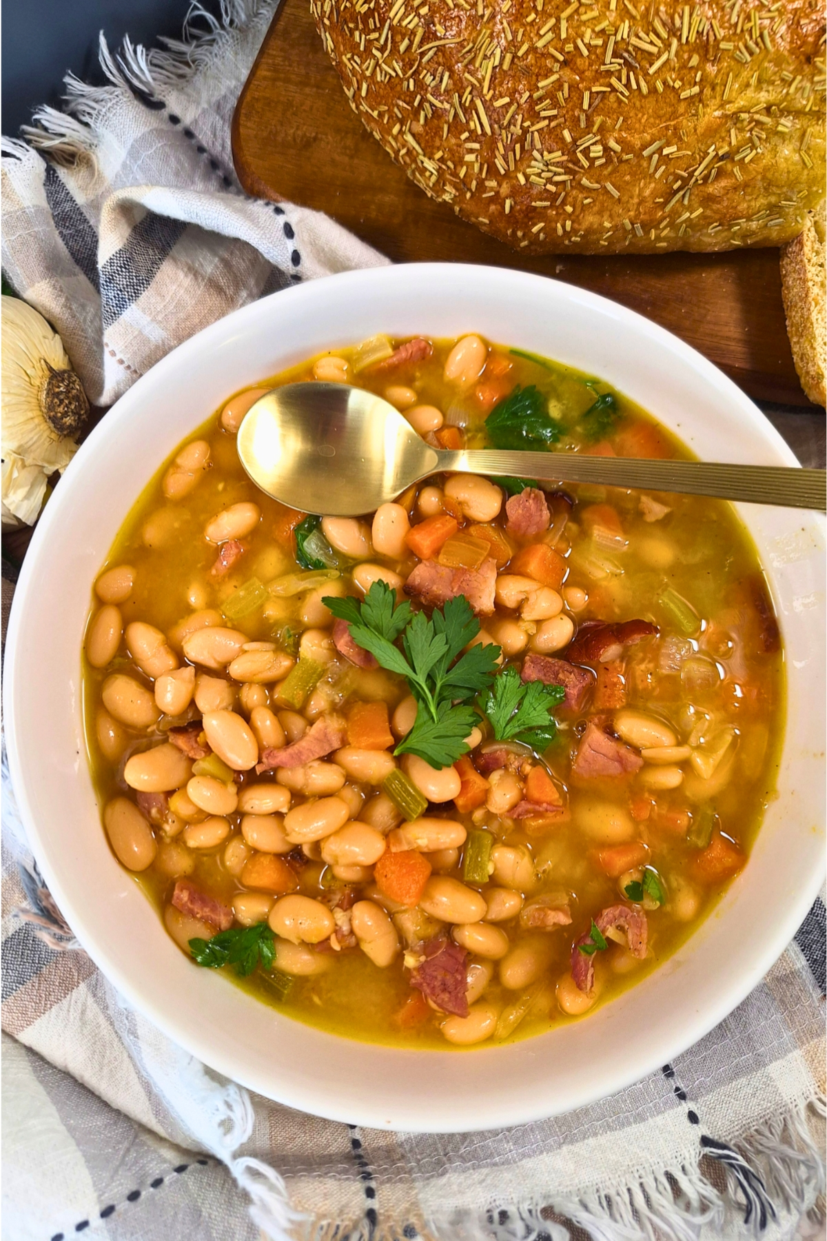 Ham and bean soup in a white bowl with parsley garnish on top.