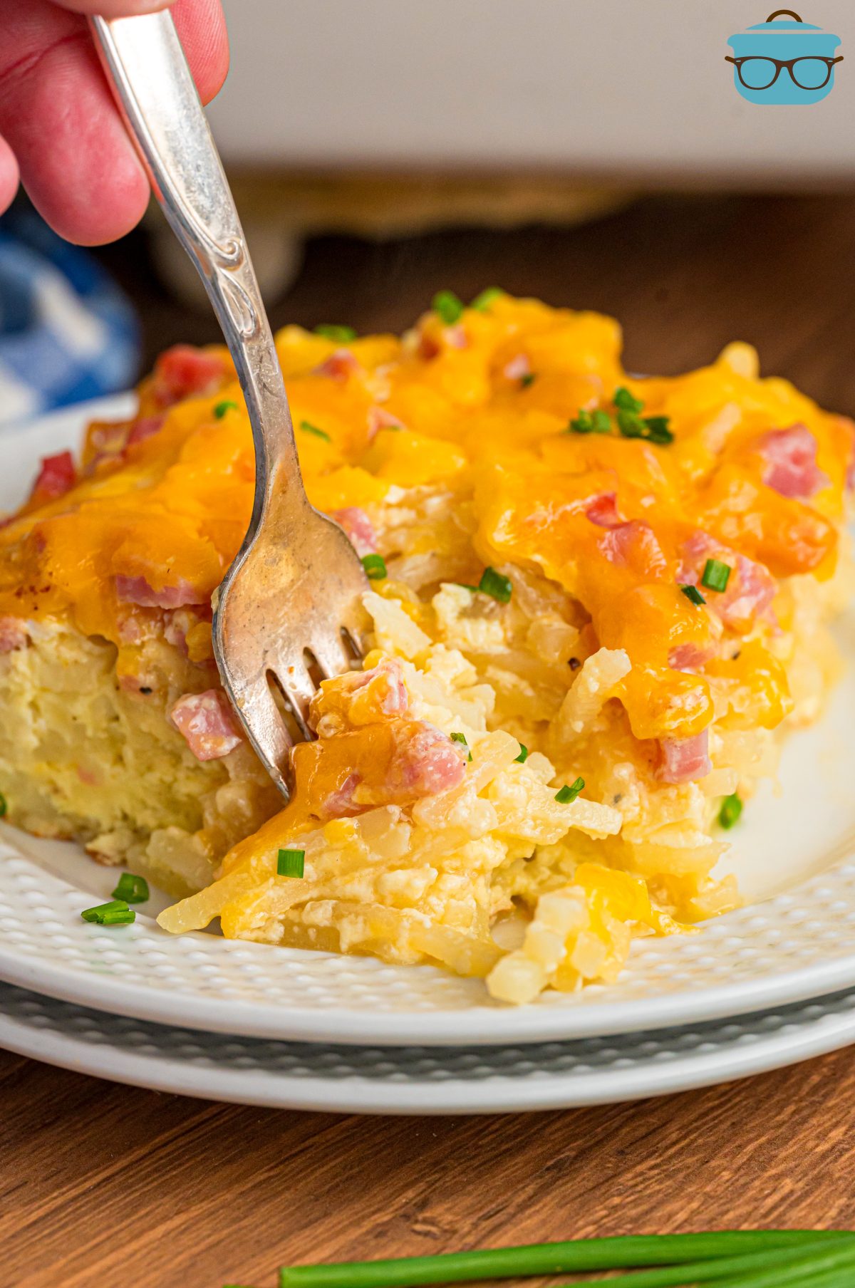 Ham and hashbrown breakfast casserole on a white plate and on a metal fork.