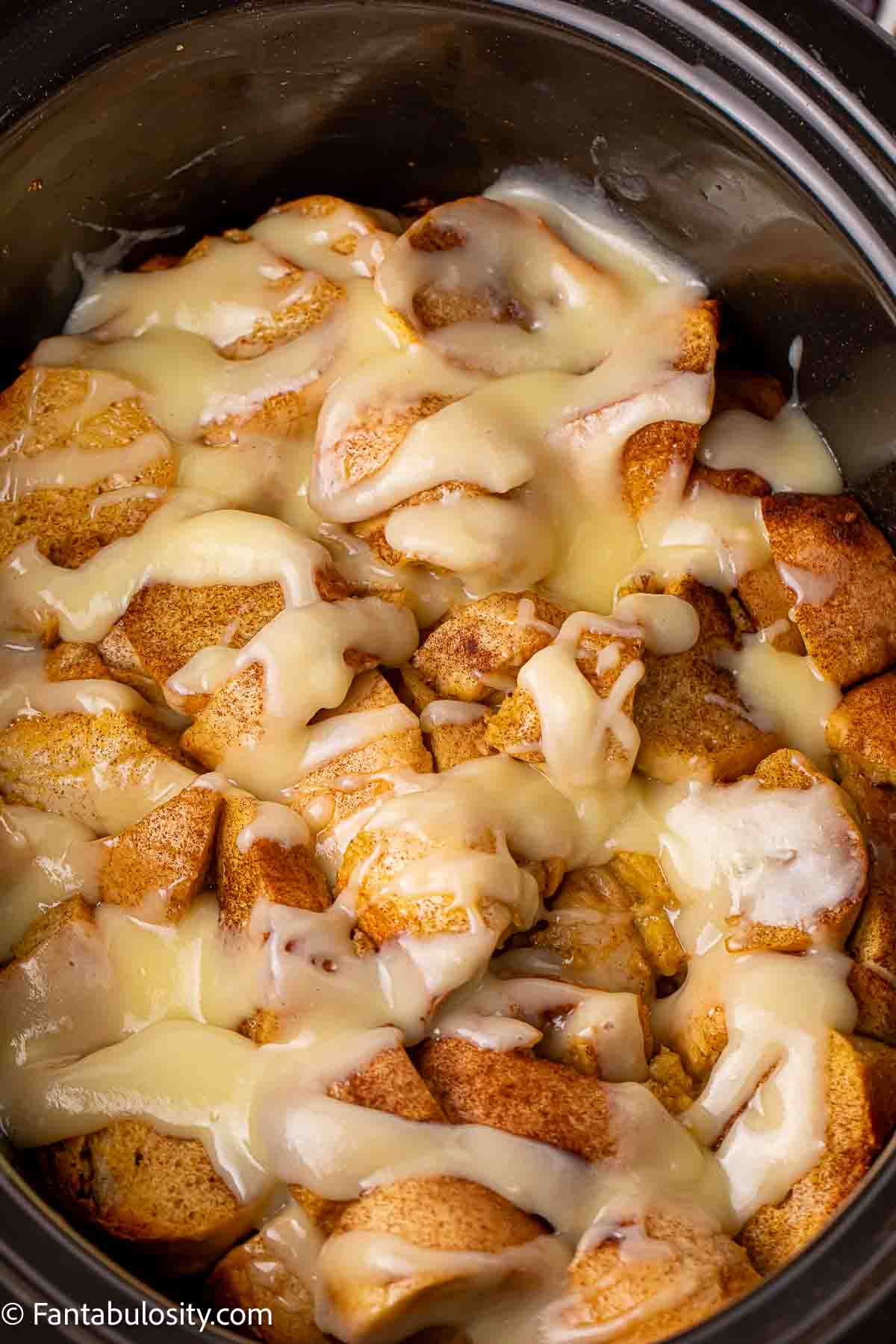 Crockpot French toast casserole with white glaze on top.