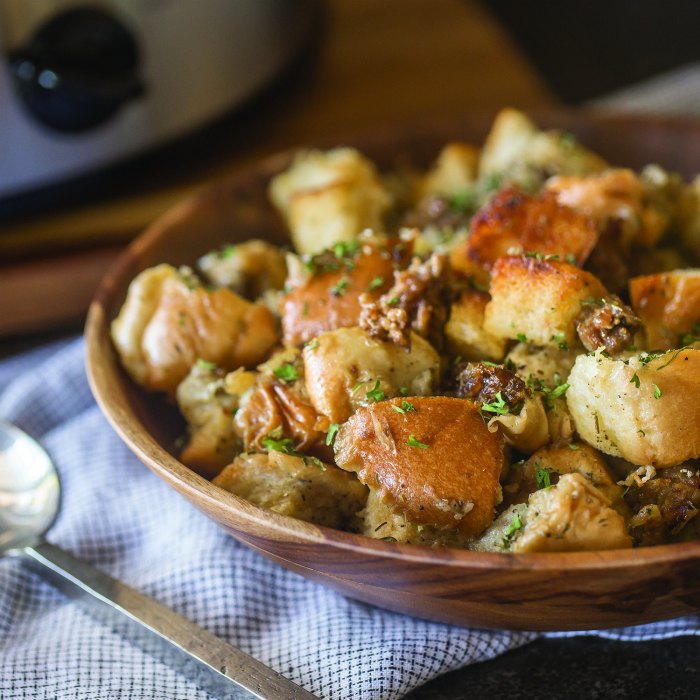 Crockpot sausage stuffing on a brown plate next to a metal spoon.