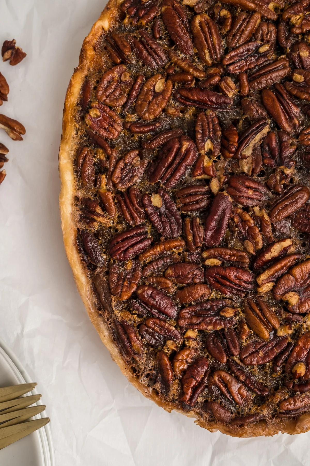 Closeup partial view of crockpot pecan pie on white parchment paper.