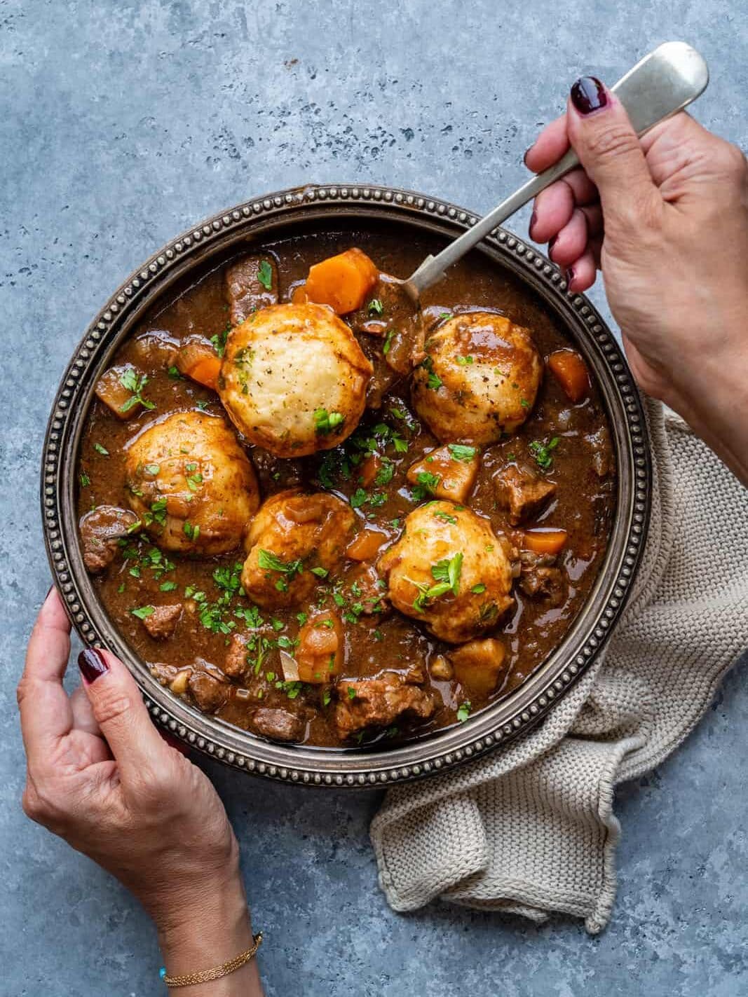 Beef and dumplings stew in a large dark bowl.